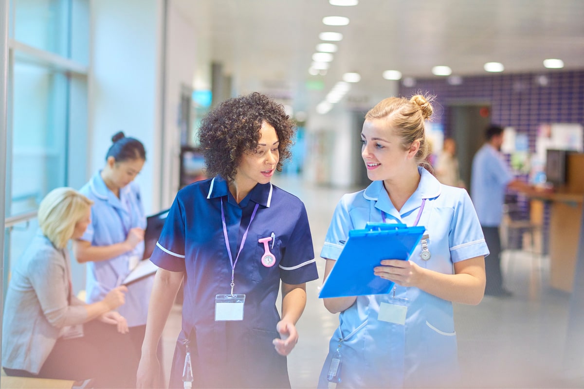 Two healthcare workers walking down hallway talking