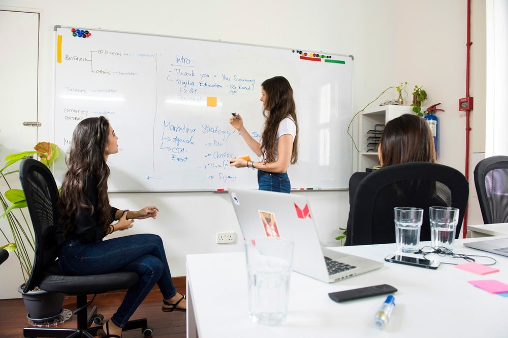 Three women sitting in office at whiteboard