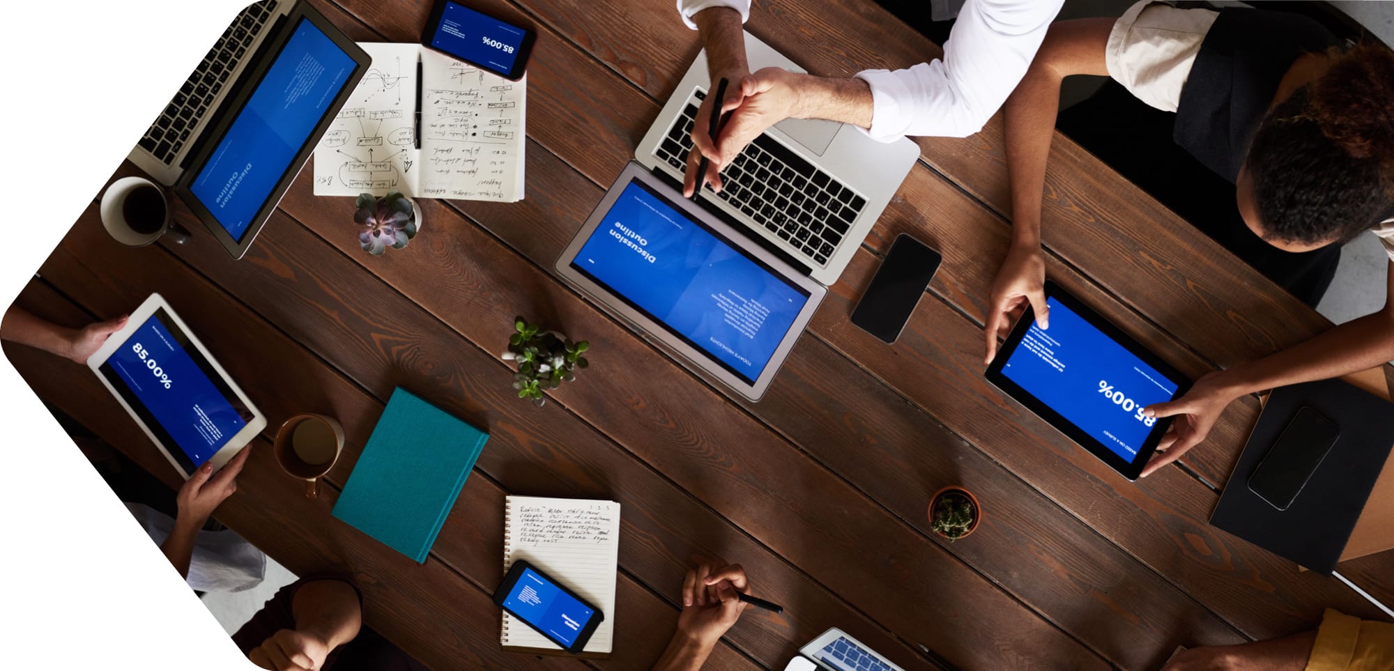 birdseye view of wooden table with tablets and laptops reviewing marketing results